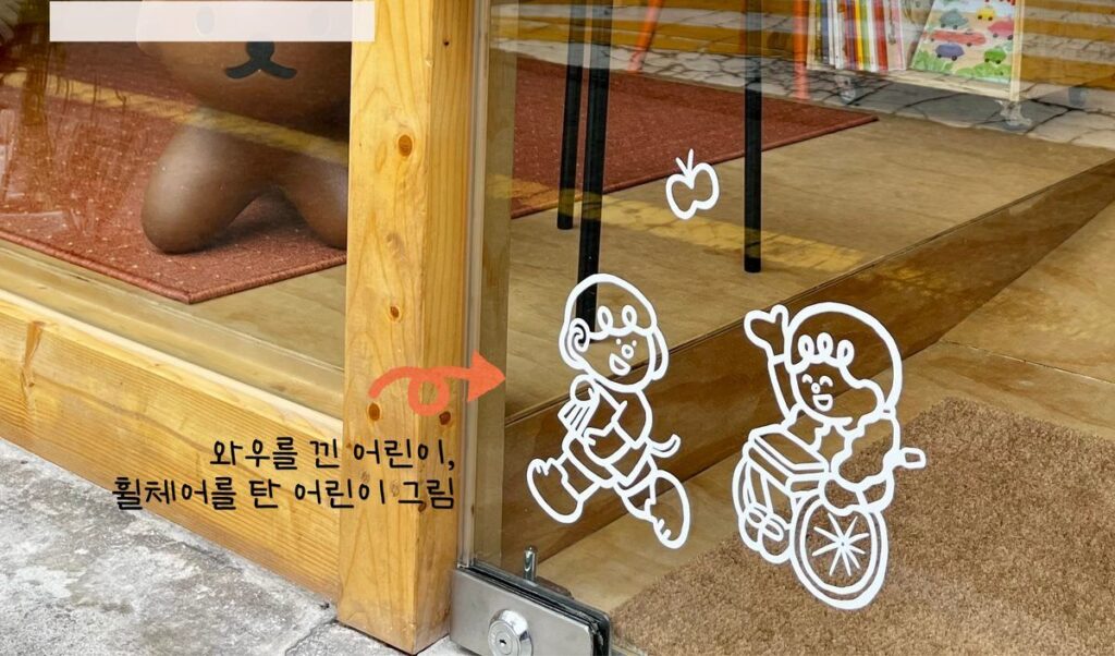 책방에 반영된 모습 — 출입문에 그려진 다양한 어린이들