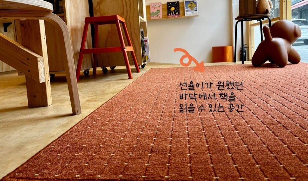 책방에 반영된 모습 — 바닥 러그 읽기 공간